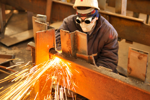 worker using torch cutter to cut through metal