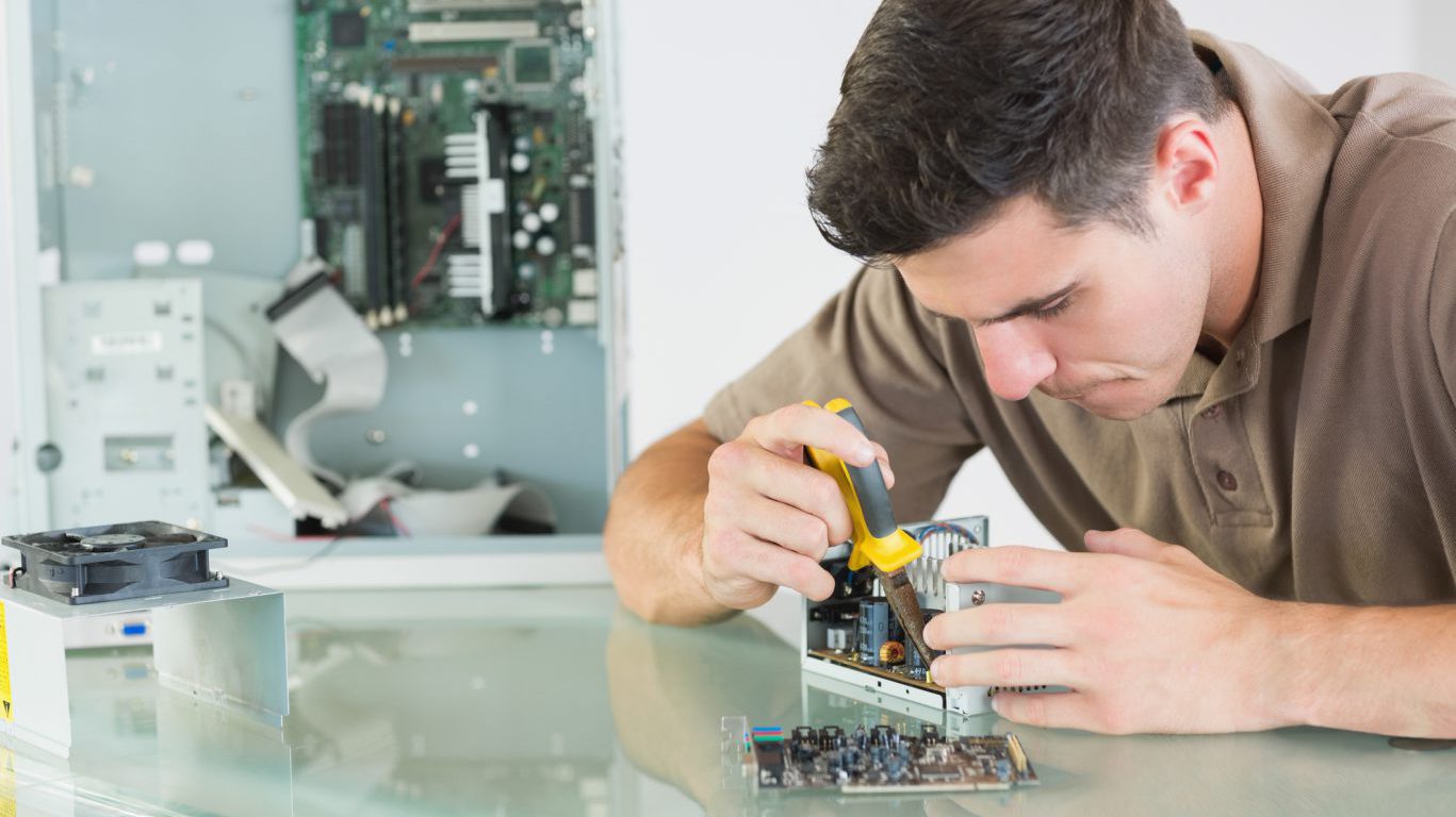 Handsome serious computer engineer repairing hardware with pliers