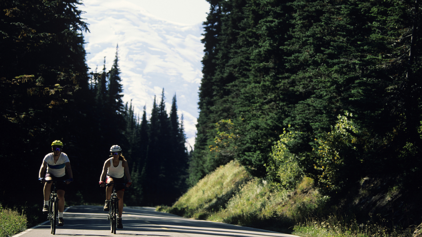 Two cyclists riding through forest, Mount Rainier National Park, Washington, USA