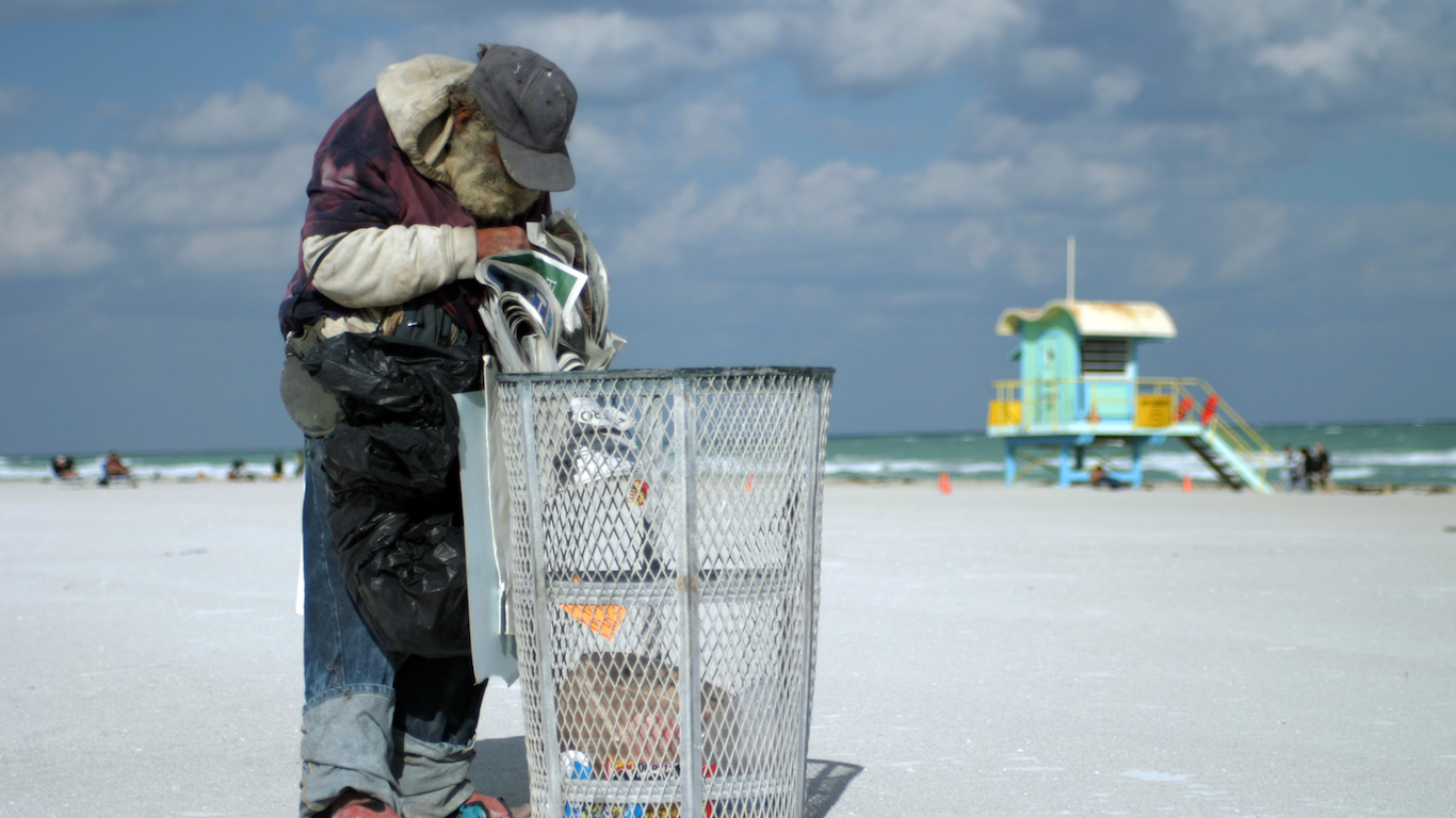 Homeless man digs through the trash for a newspaper on Miami&#039;s South Beach, Florida