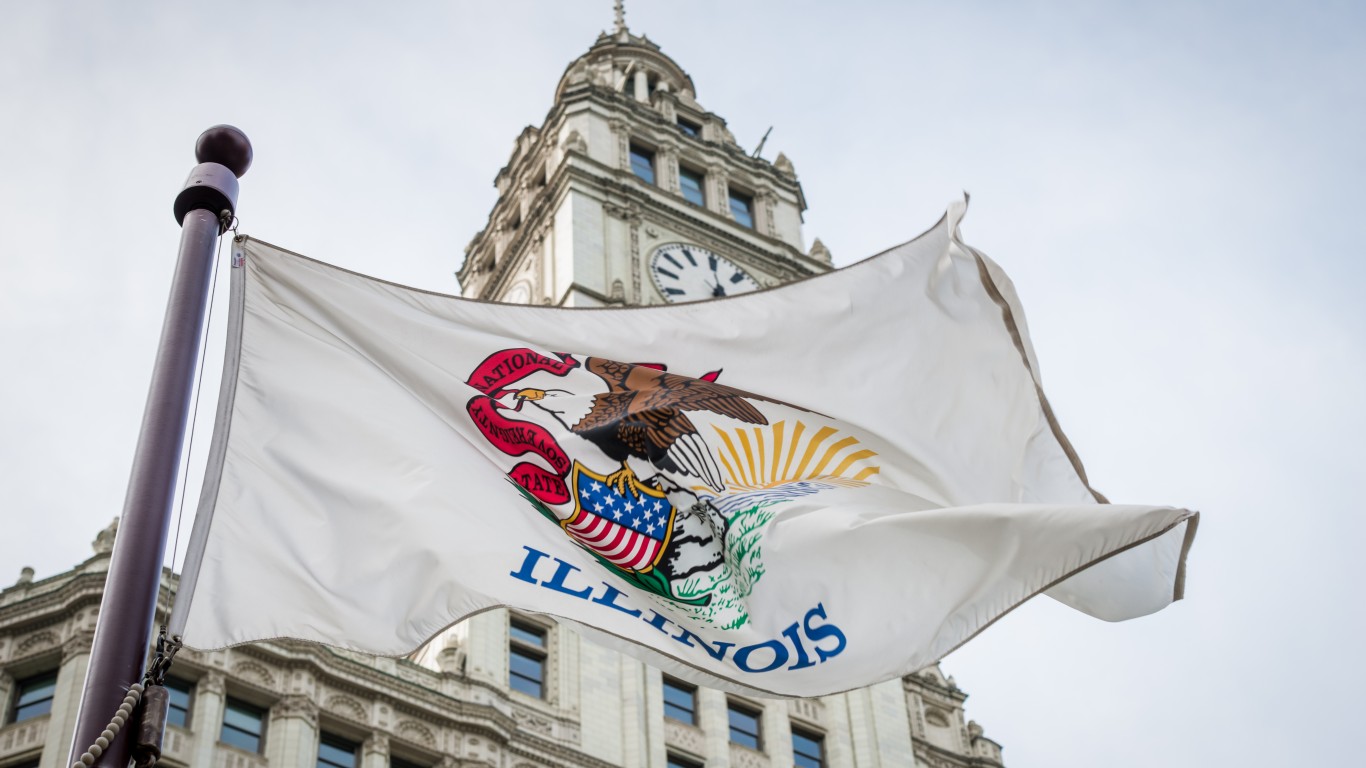An Illinois state flag waving in the foreground of the iconic Wrigley building.