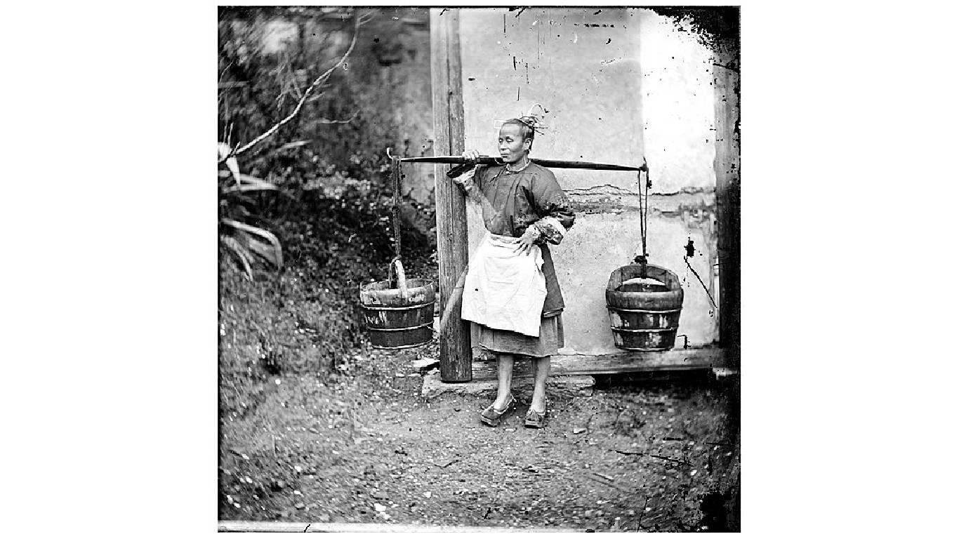 China; a woman carrying buckets of night-soil by John Thomson