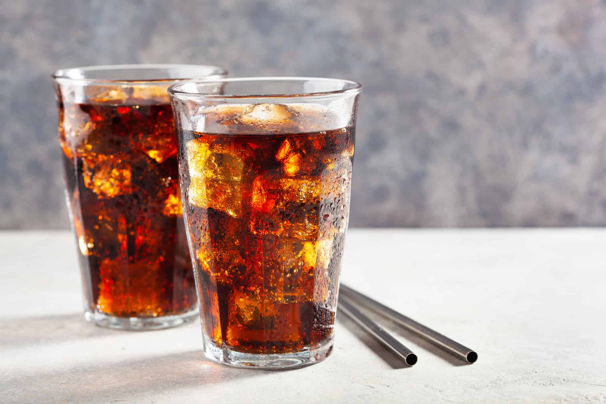 glass of cold cola soft drink with ice on wooden background