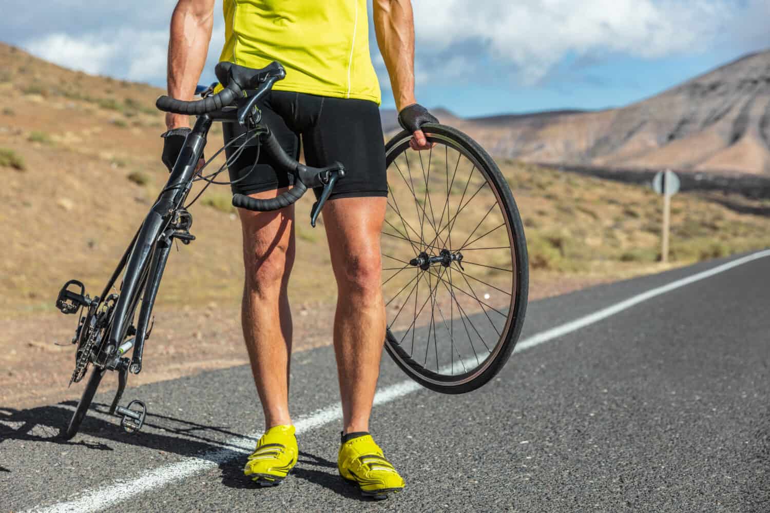 Bike repair cyclist man on side of road repair road bicycle problem with wheel. Cycling outdoor athlete biker biking with cycle.