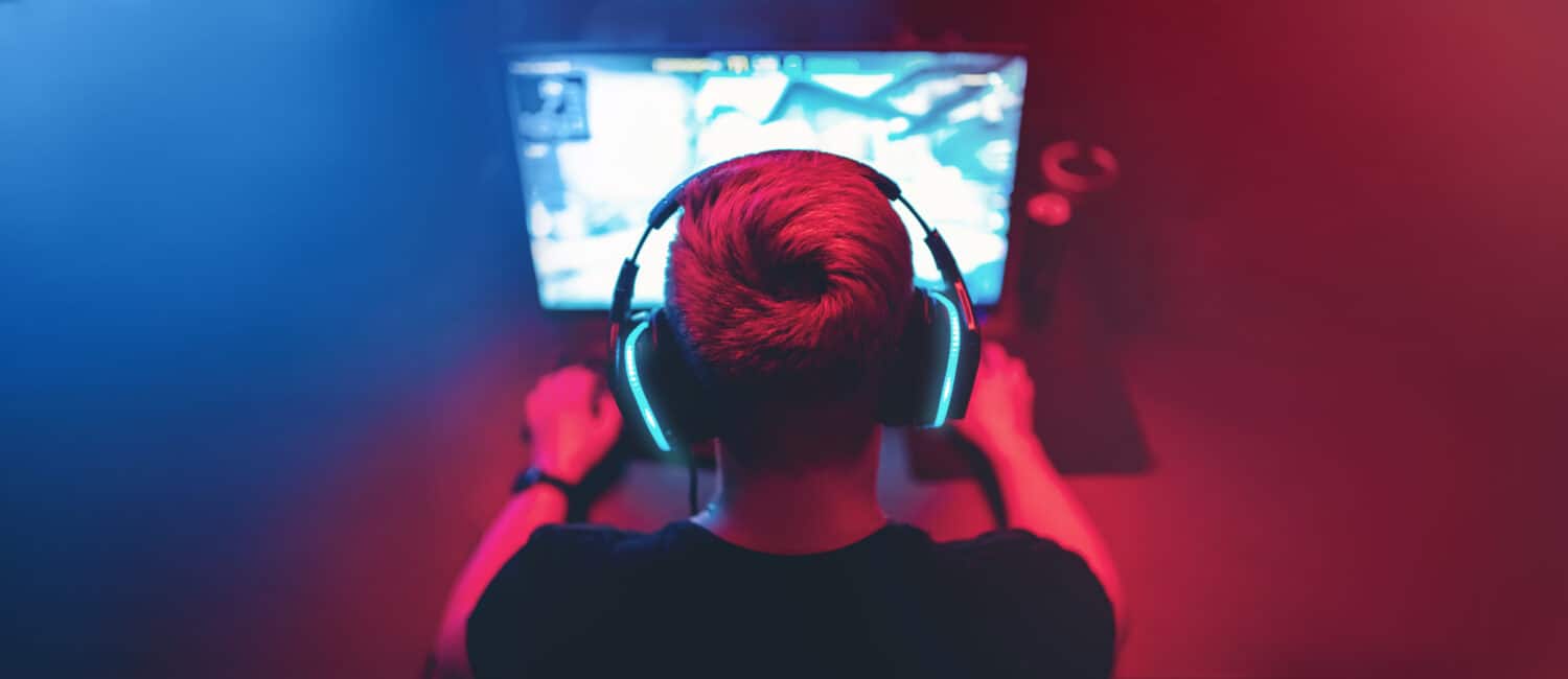 Background professional gamer playing tournaments online games computer with headphones, red and blue.