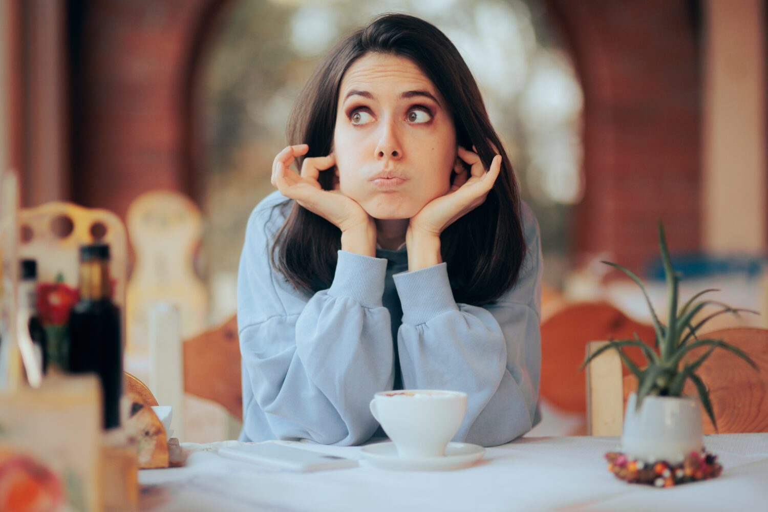 Annoyed Woman Covering Her Ears in Noisy Restaurant. Unhappy cafeteria customer complaining about the environmental noise