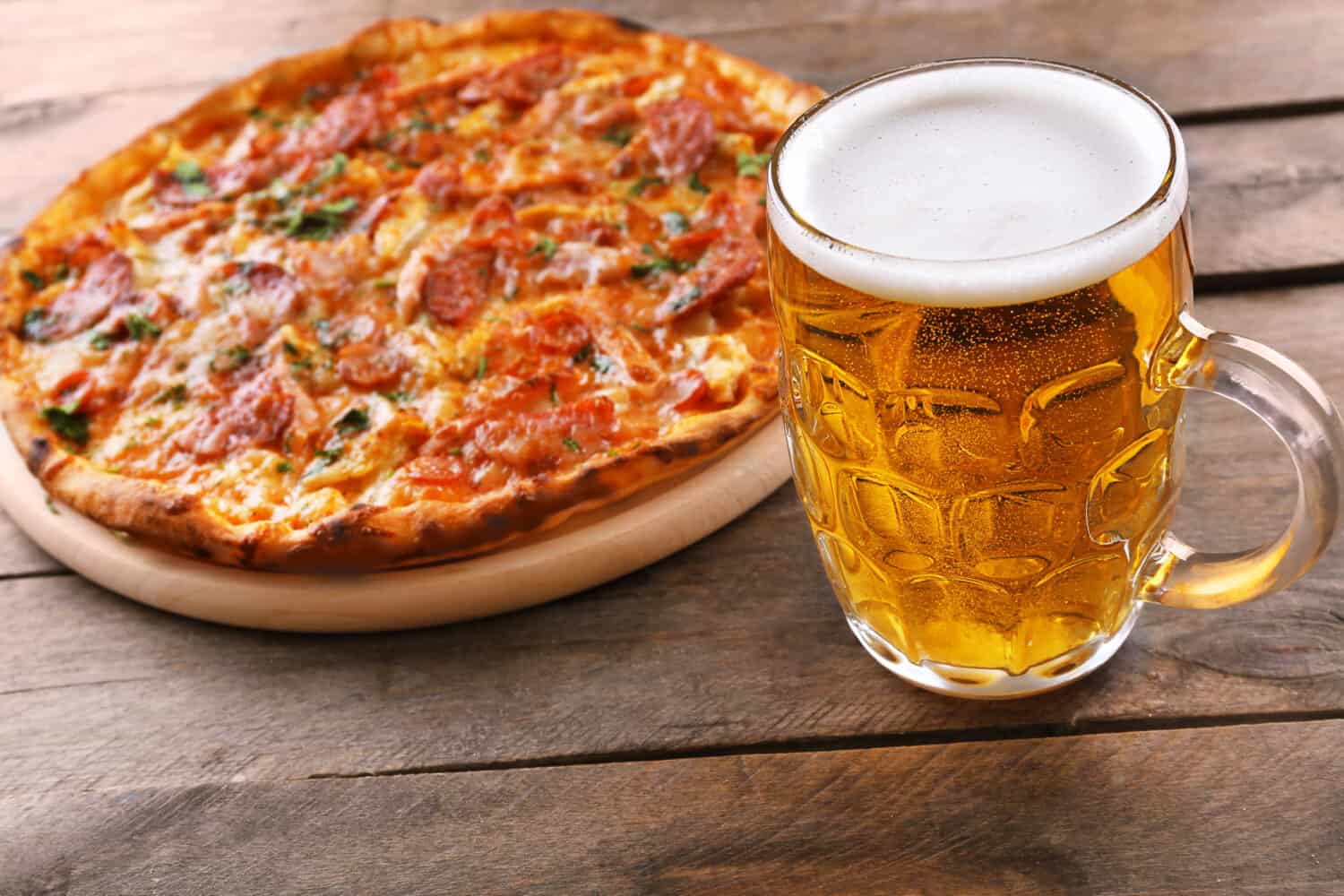 Tasty pizza and glass of beer are on wooden table, close up