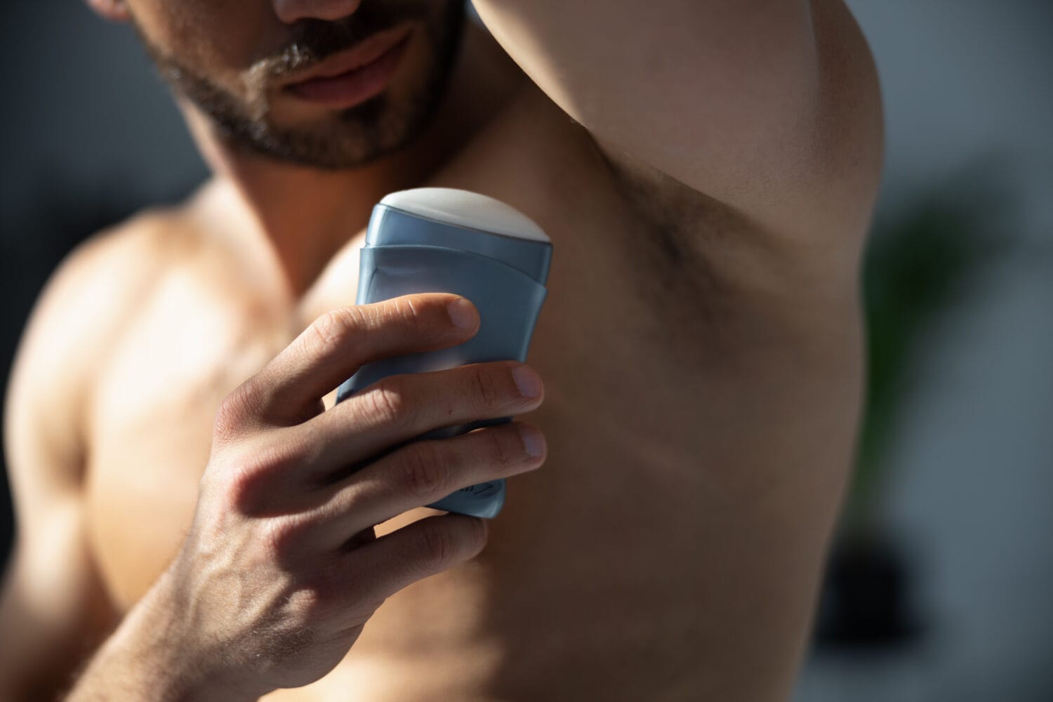 Close up shot of young handsome man with muscle body using deodorant