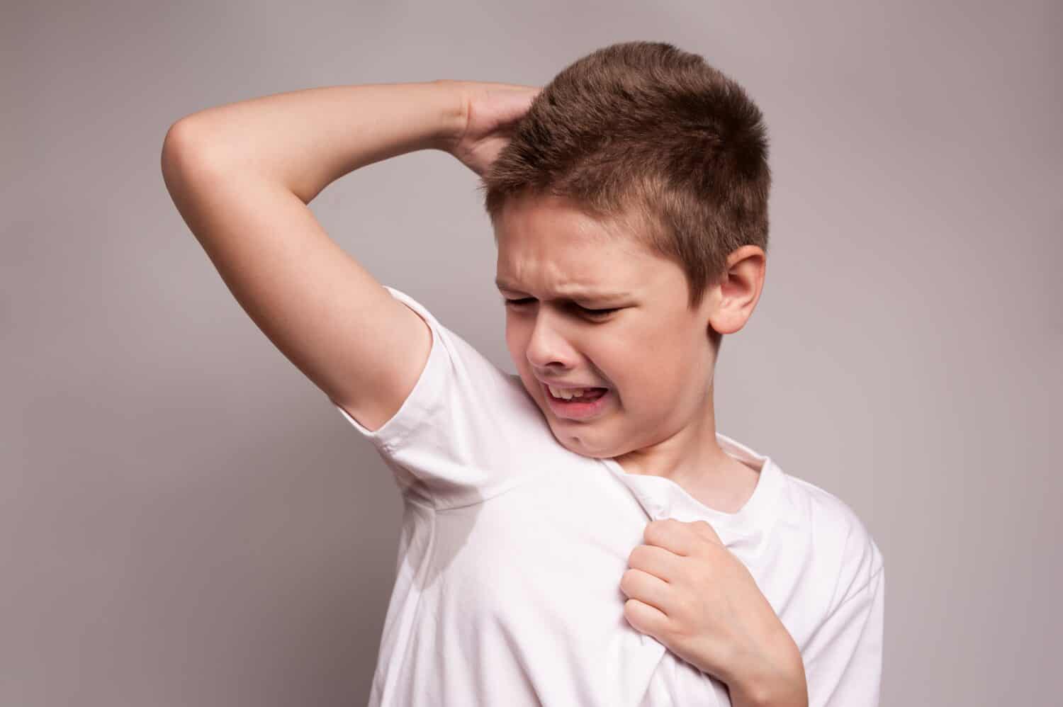 the boy sniffs the unpleasant smell of a sweaty T-shirt