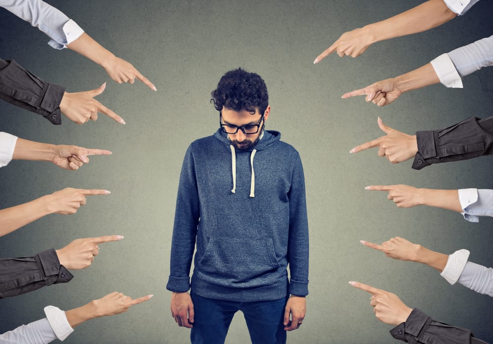 Plenty of crop hands fingers pointing at young man feeling guilty and being introvert.