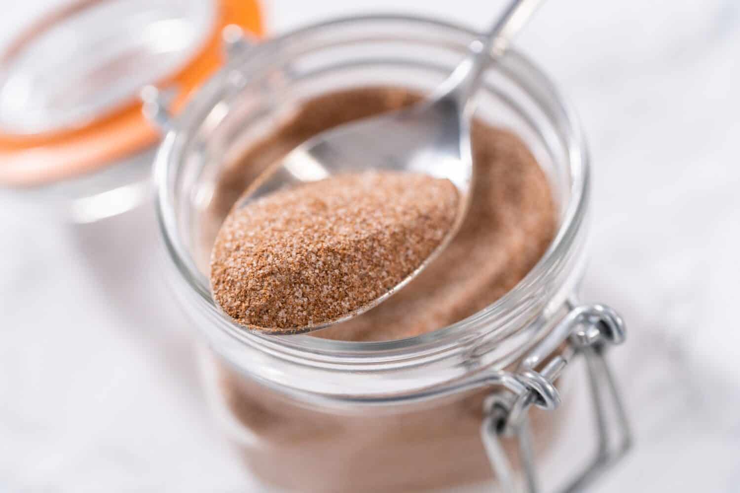 Cinnamon sugar in a glass mason jar on the marble surface.