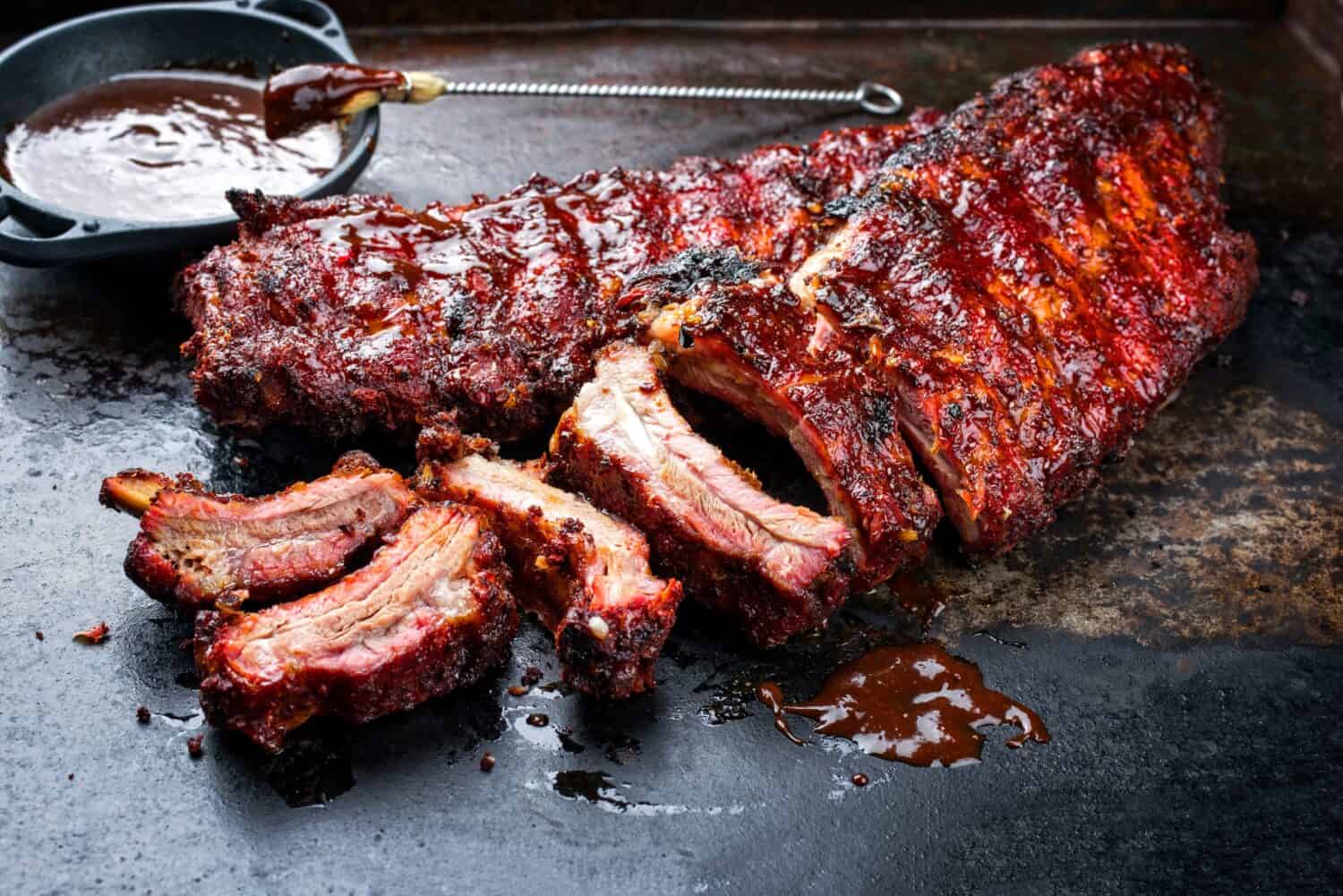 Barbecue pork spare loin ribs St Louis cut with hot honey chili marinade burnt as closeup on an old rustic board