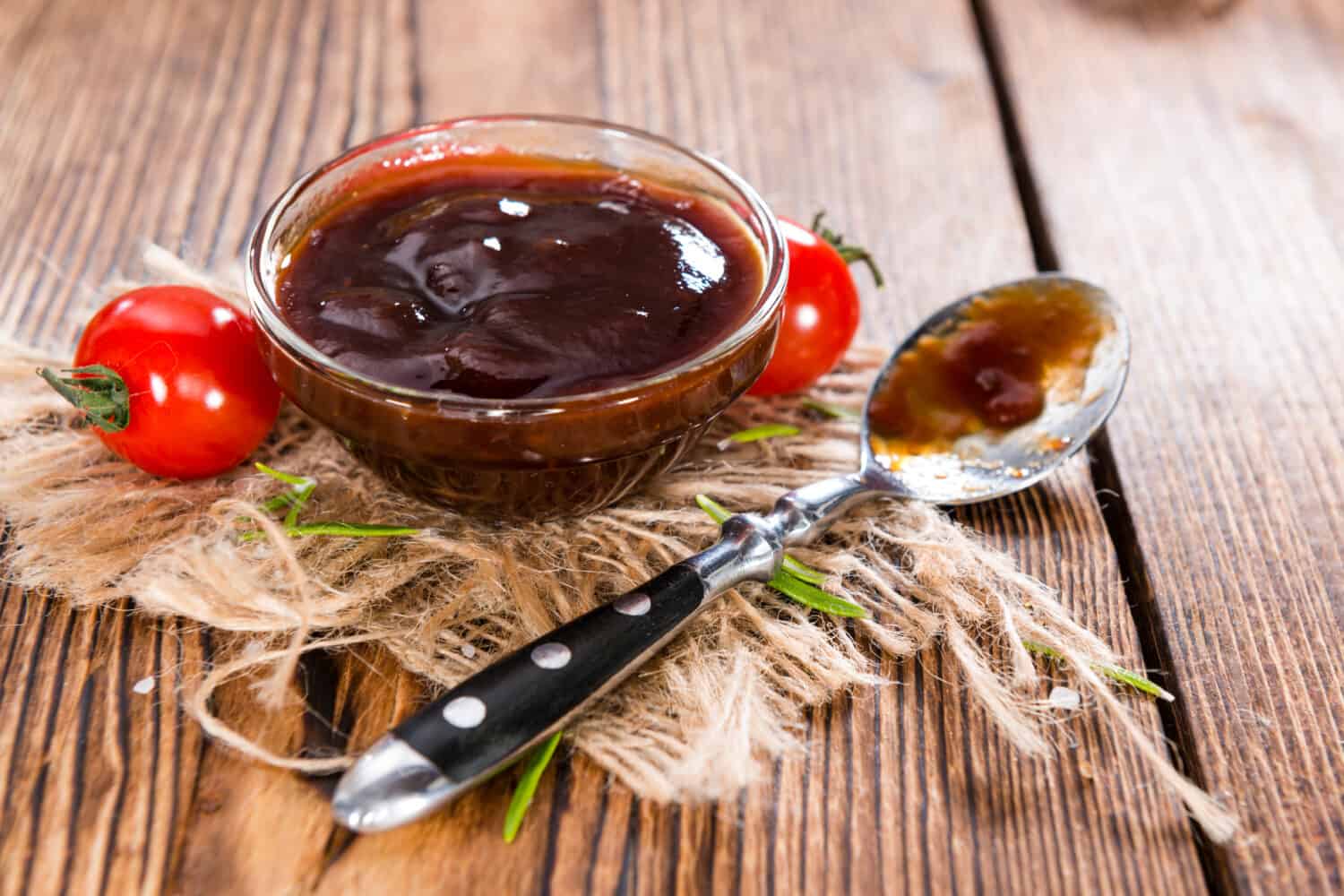 Barbeque Sauce with Tomatoes, Smoked Salt and fresh Herbs (on rustic wooden background)