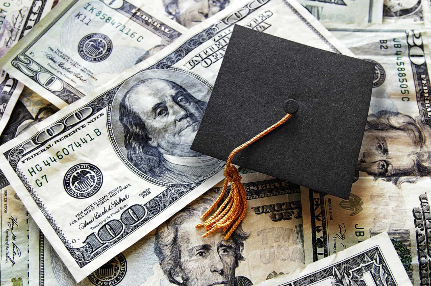 Miniature graduation cap on hundred dollar bills