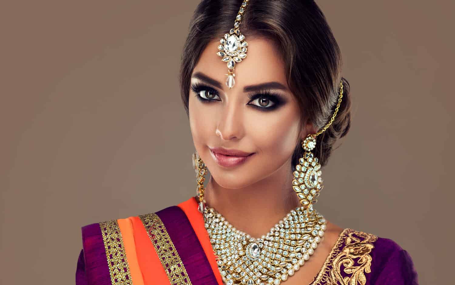 Portrait of beautiful indian girl . Young hindu woman model with tatoo mehndi and kundan jewelry . Traditional Indian costume lehenga choli .