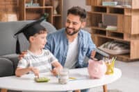 Little boy and father with savings for education and calculator at home