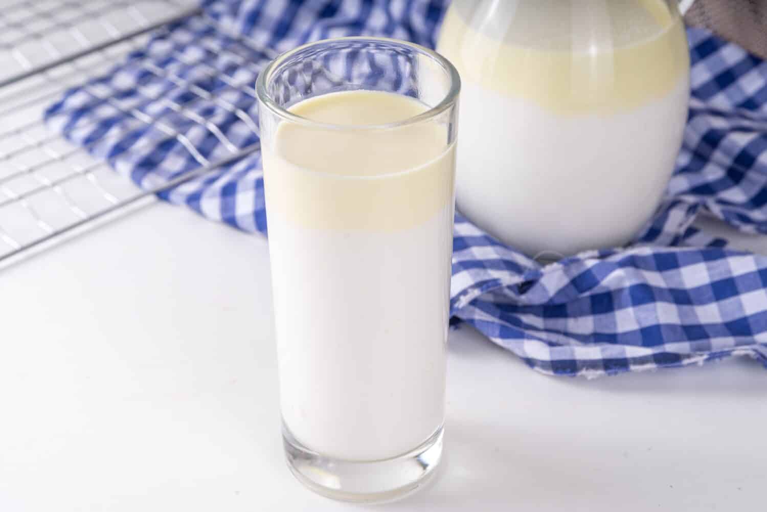 Non-Homogenized, whole milk, cream-top layered dairy product, Creamline Milk concept. Organic farm natural, unpasteurized milk in glass and jug, on white kitchen table copy space