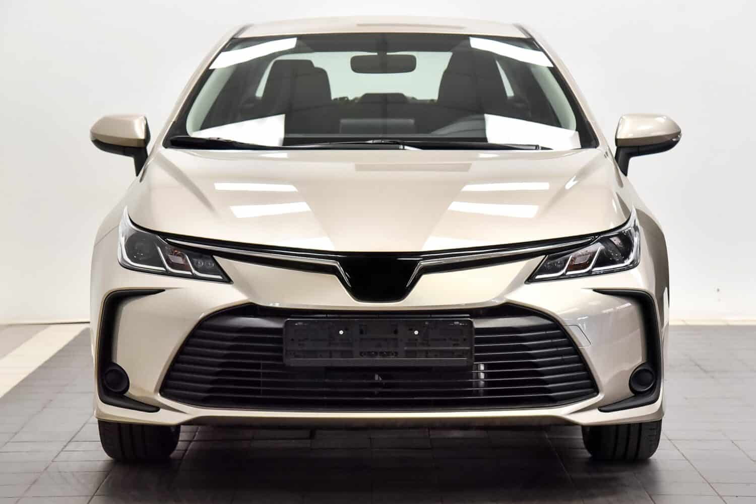 A beige car on a white background stands indoors.