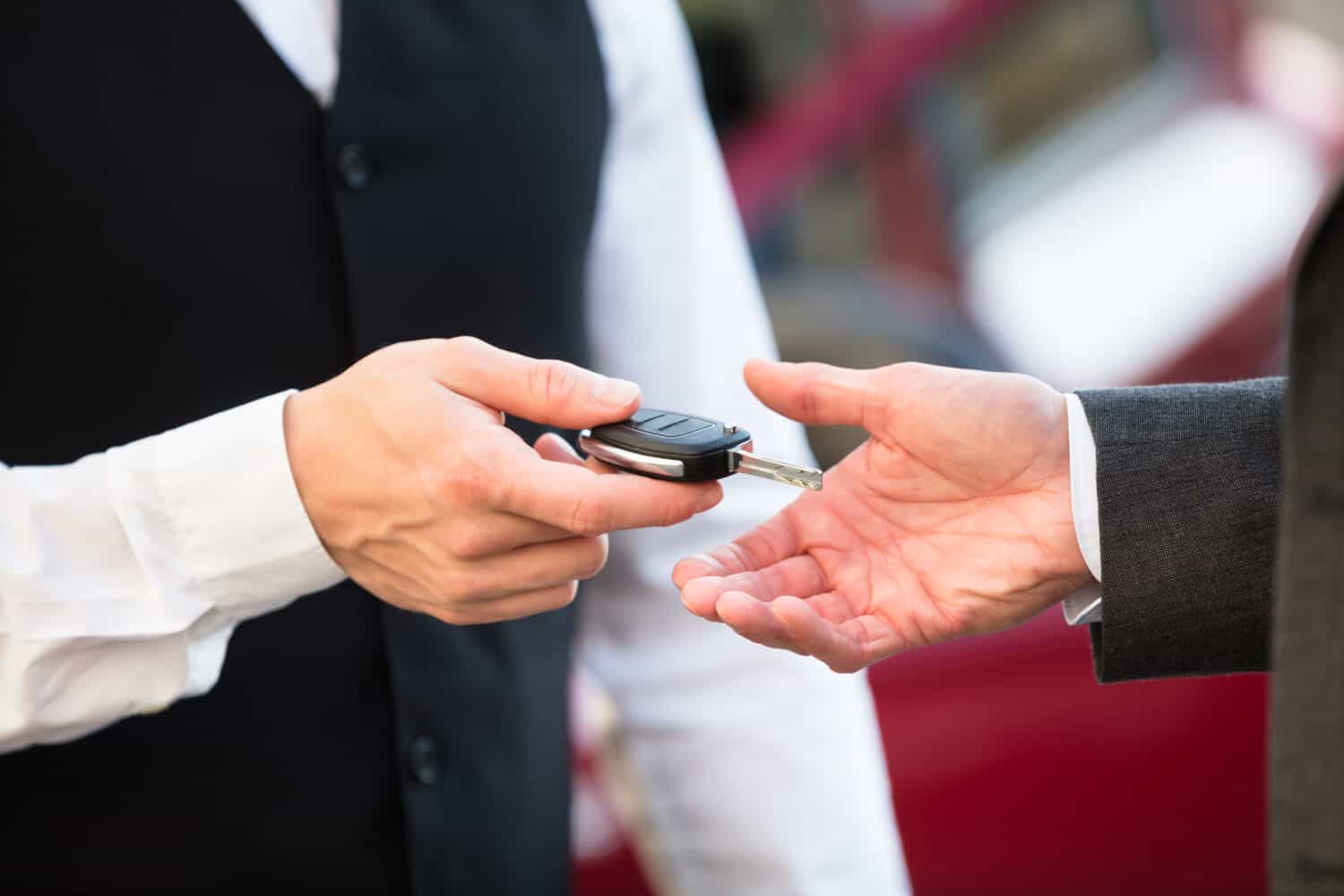 Close-up Of Valet&#039;s Hand Giving Car Key To Businessperson