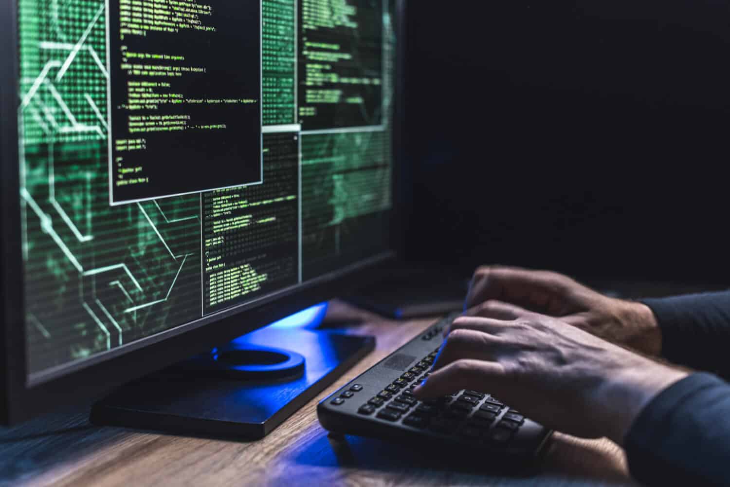 Close-up of Caucasian man hands typing data on a keyboard, cyberspace seen on a computer monitor