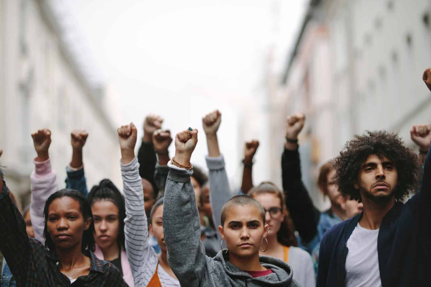 Group of protestors with their fists raised up in the air. Activists protesting on the street.