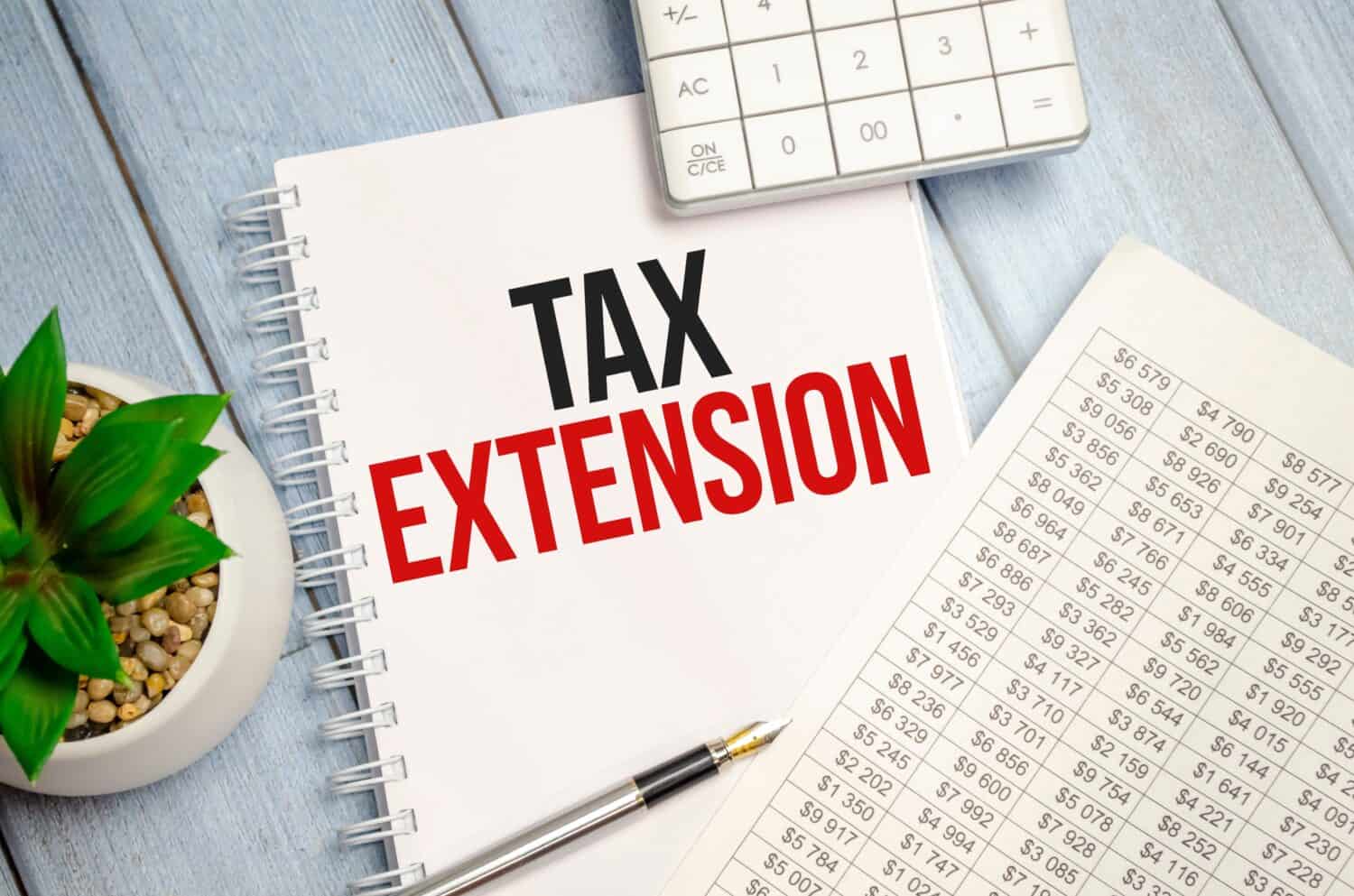 TAX EXTENSION text on paper with calculator, notepad and charts