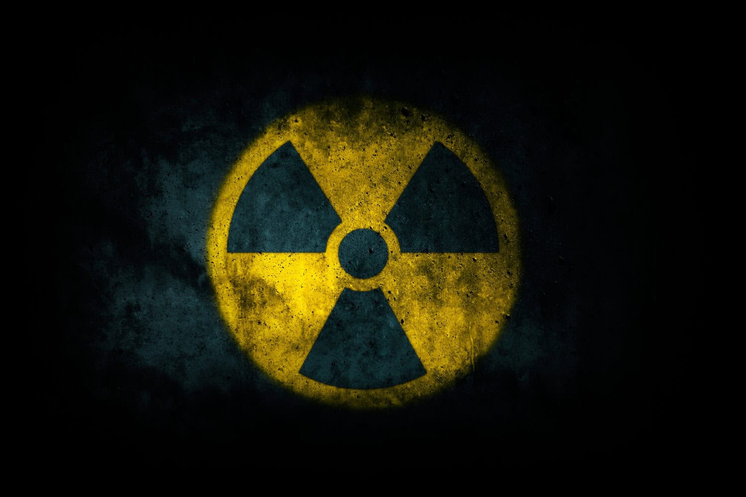 Nuclear energy radioactive (ionizing atomic radiation) round yellow symbol shape painted on massive concrete cement wall texture dark background. Nuclear radiation or radioactive alert warning danger.