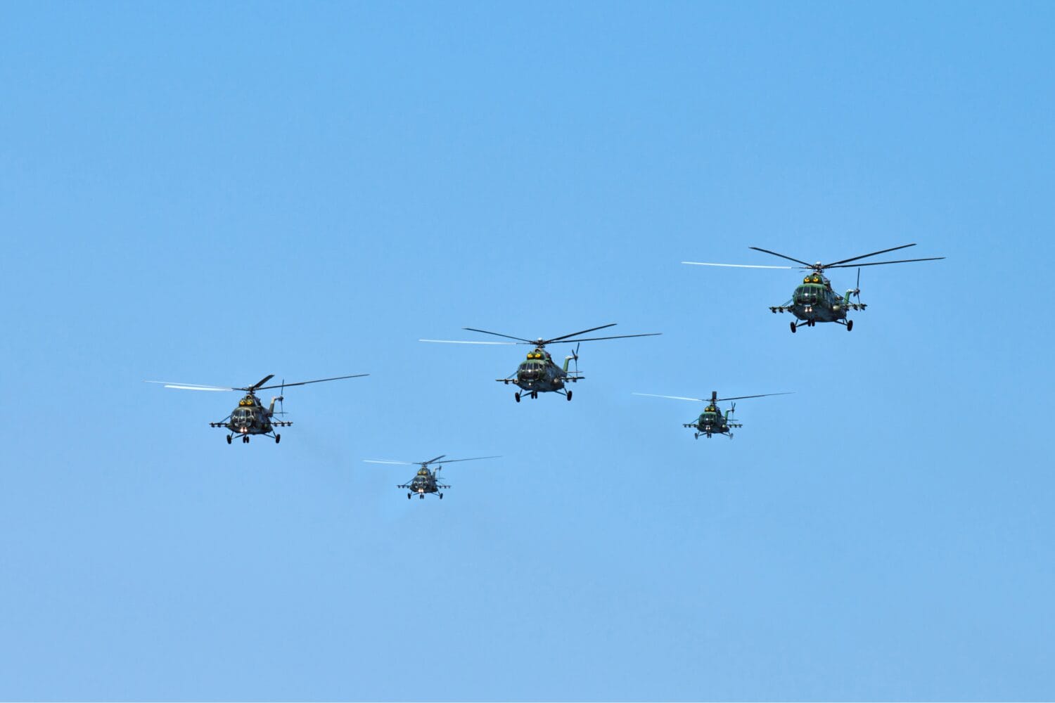 Military helicopters flying in bright blue sky performing demonstration flight, airforce, copy space. Group combat helicopters, aerobatic team performs flight at air show