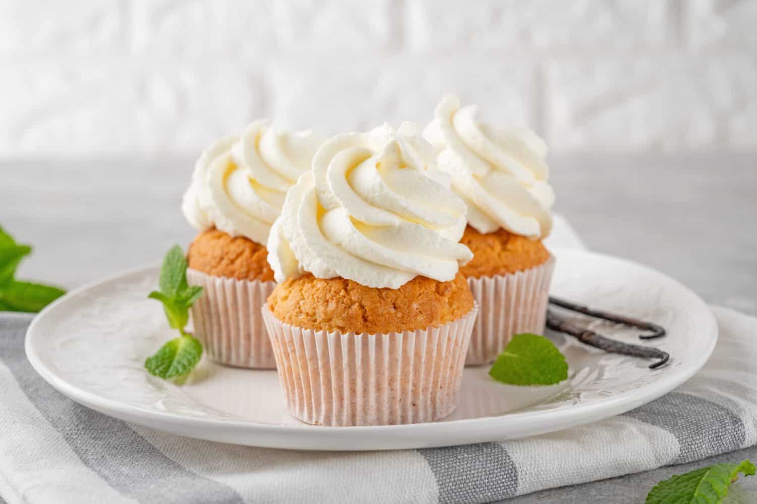 Delicious vanilla cupcakes with cream cheese and sugar candy on a gray background. Dessert for birthday. selective focus, copy space