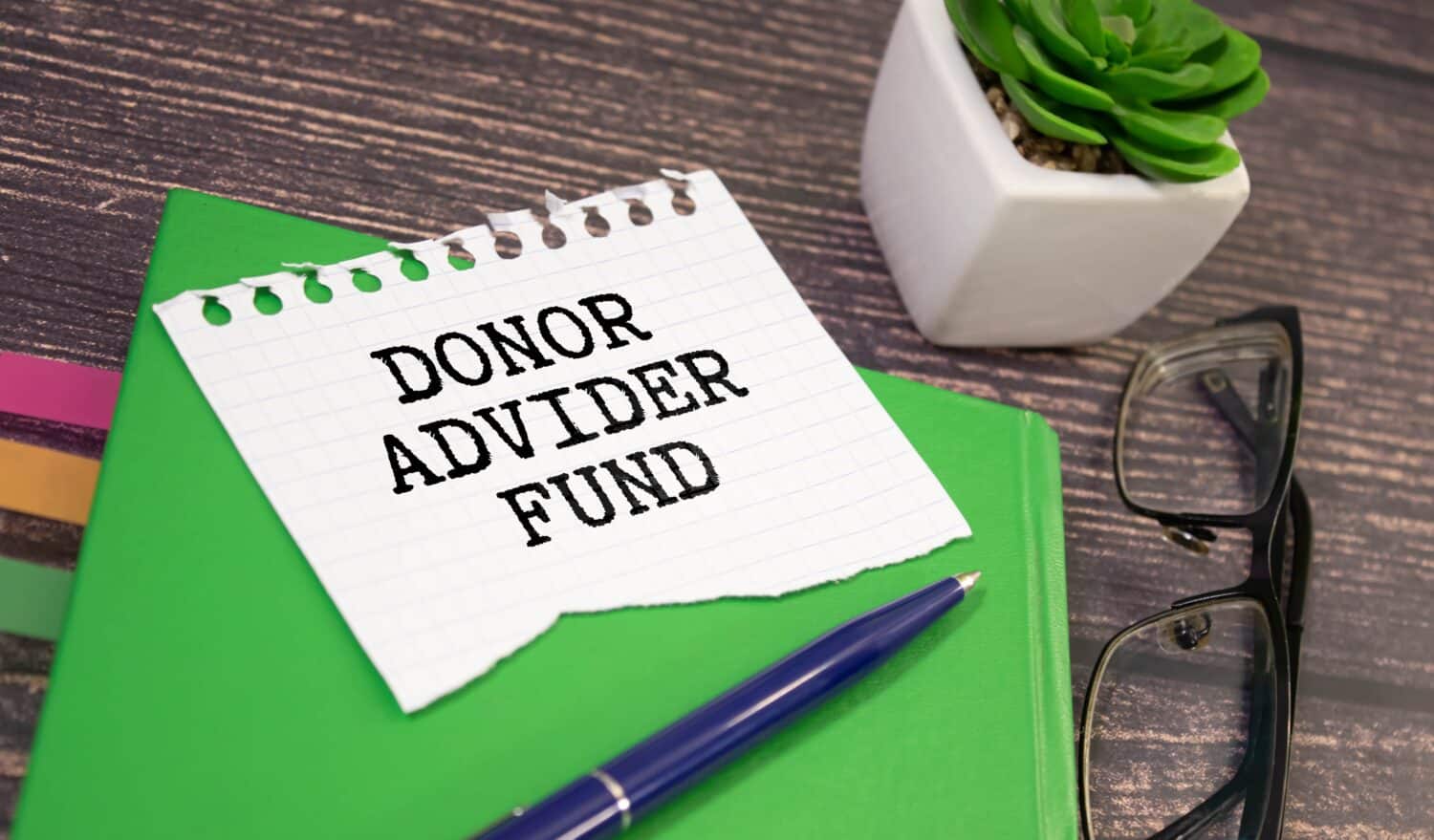 Home office workplace with clipboard and pen with DONOR ADVIDER FUND text on white wooden background, business.