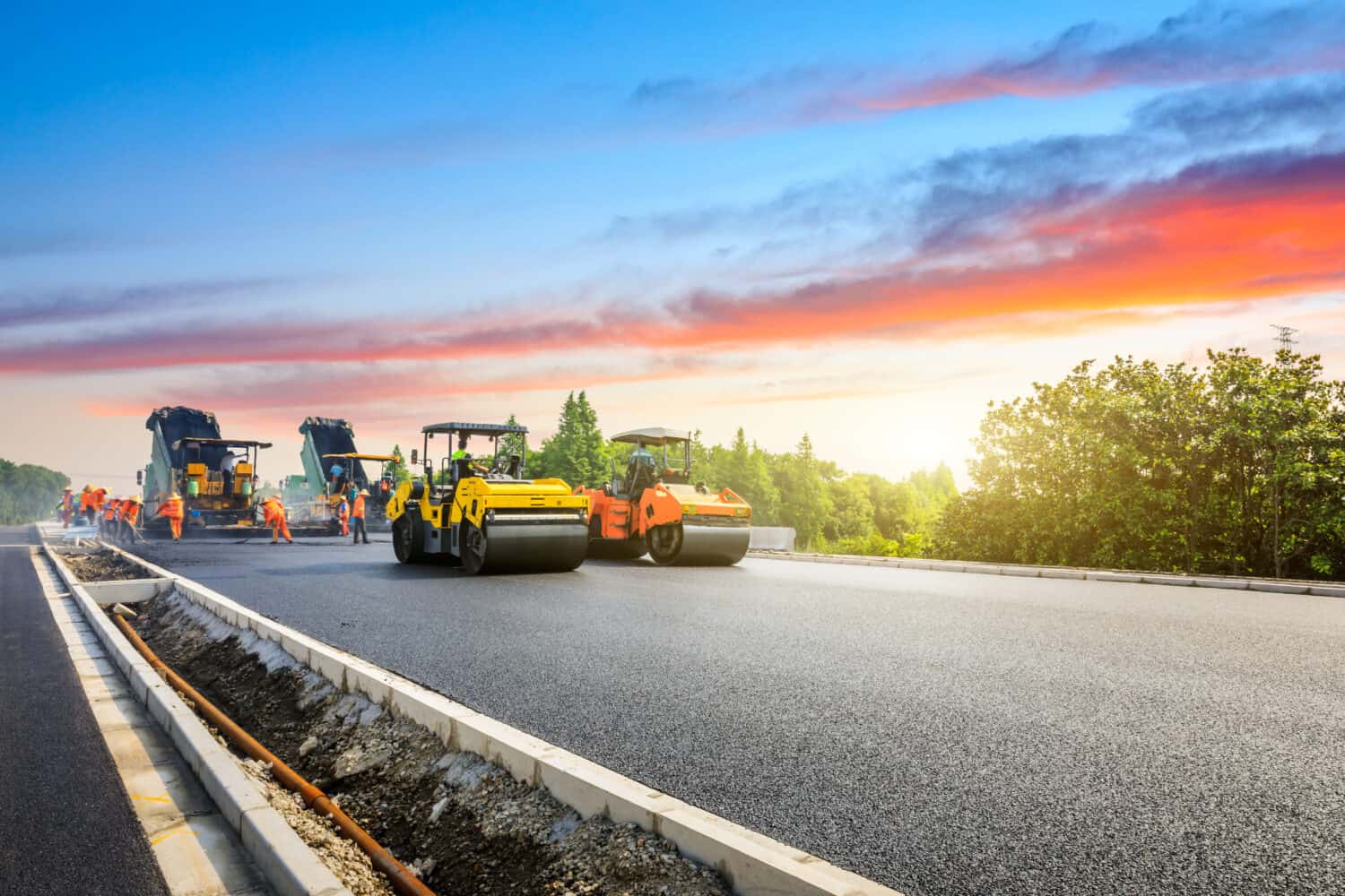 Construction site is laying new asphalt road pavement,road construction workers and road construction machinery scene.highway construction site landscape.