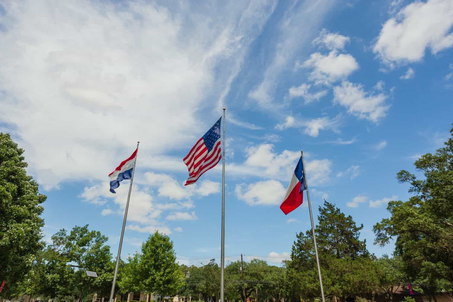 Three flags in the wind: United States, State of Texas, and the town of Friendswood, TX