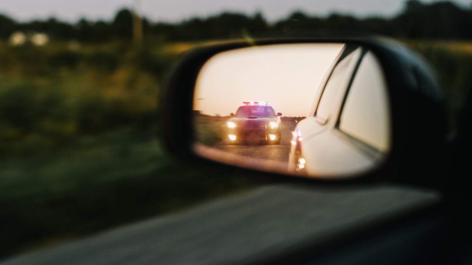 Stylish Side Mirror Car Chase Shot: Highway Traffic Patrol Vehicle Pull over Suspect. Professional Female Police Officer Approaches Vehicle, Asks Driver License and Registration. Cinematic Shot