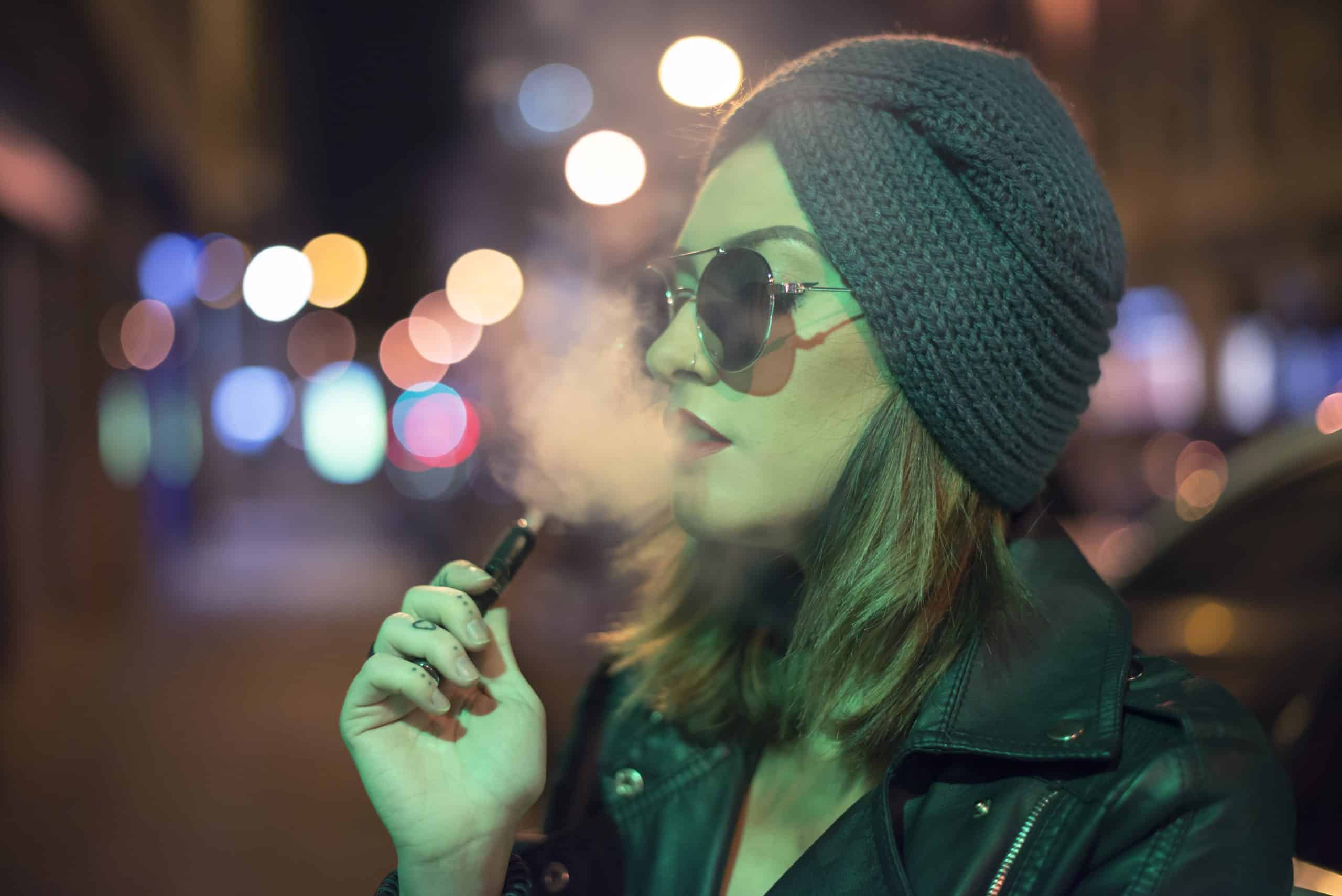 Young woman smokes electronic cigarette.