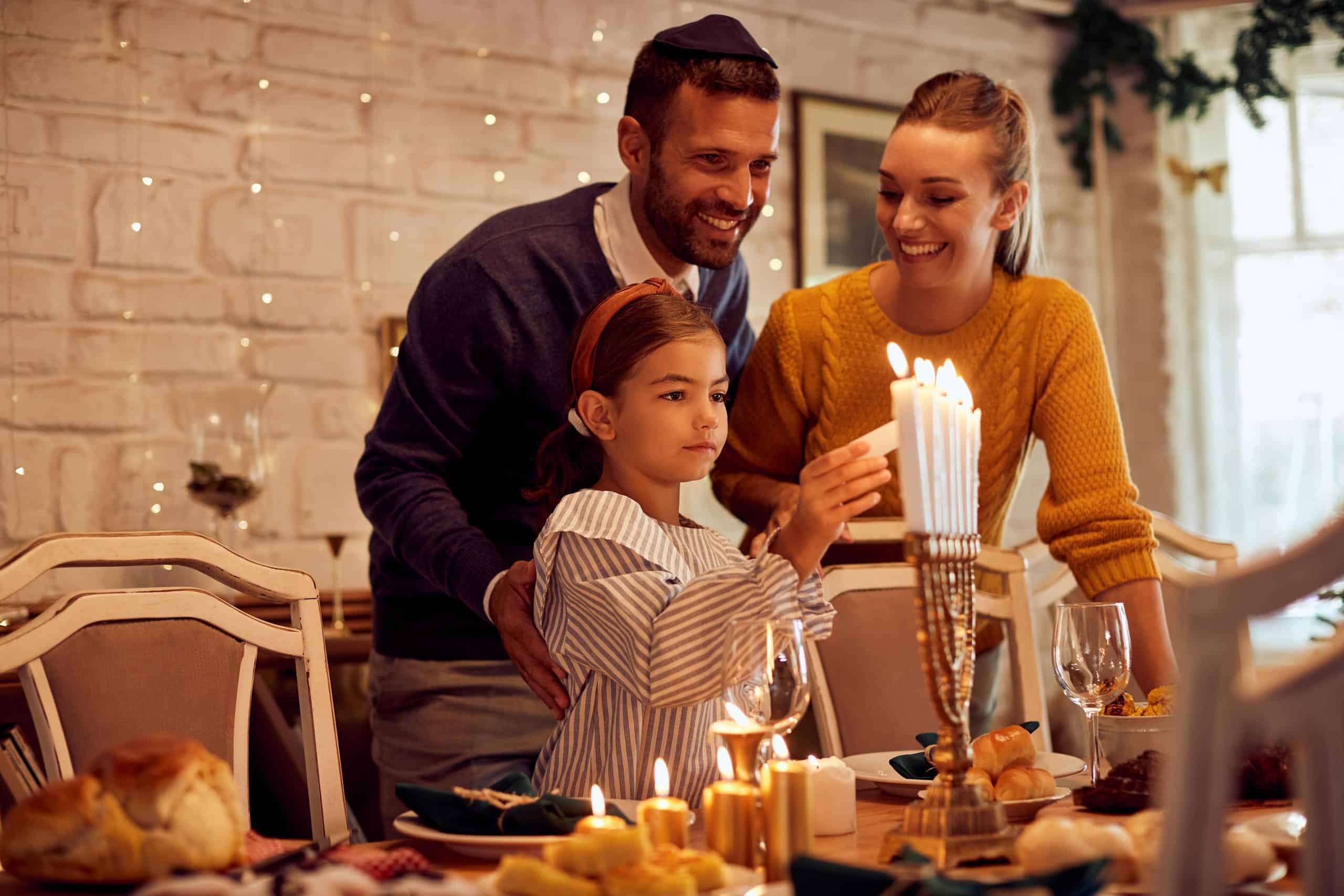 jewish family | Happy Jewish family lightning the menorah before a meal at dining table.