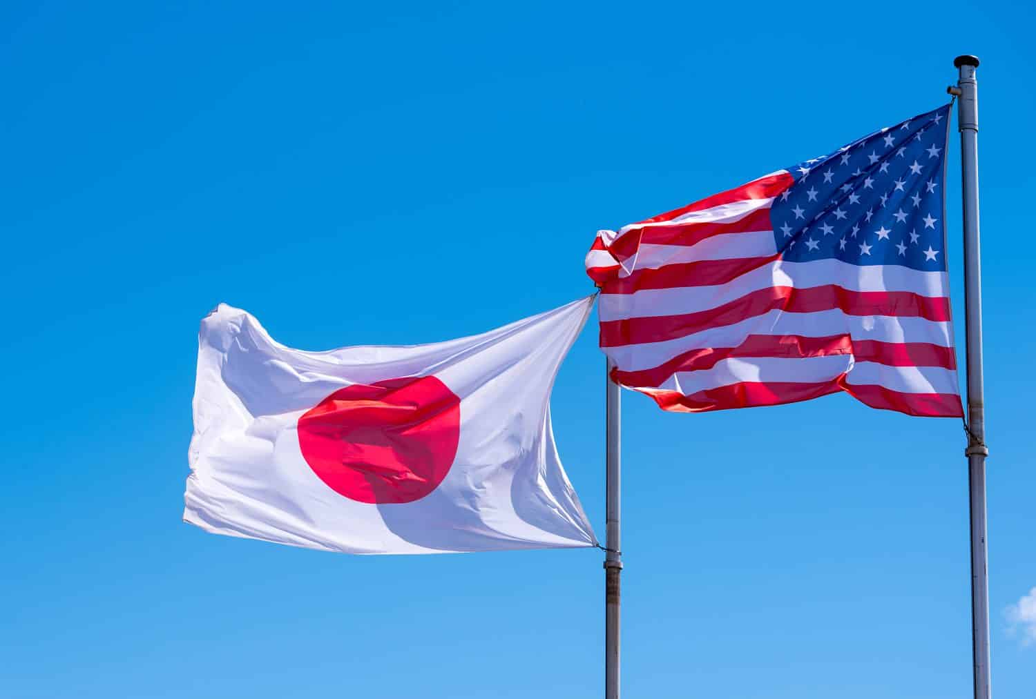 American and Japanese Flags waving against blue Sky