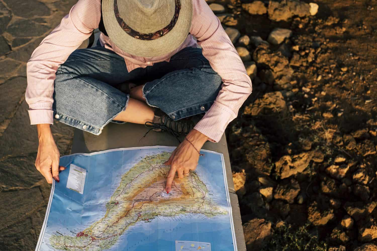 above aerial view of nice adventurer woman looking on the map for her next stop and destination place loceation. tourism and alternative way to travel and discover the world. wanderlust and happiness