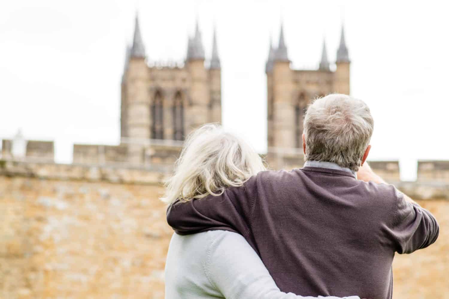 A elderly couple exploring in their retirement, pointing and looking at Loncoln cathedral in the distance