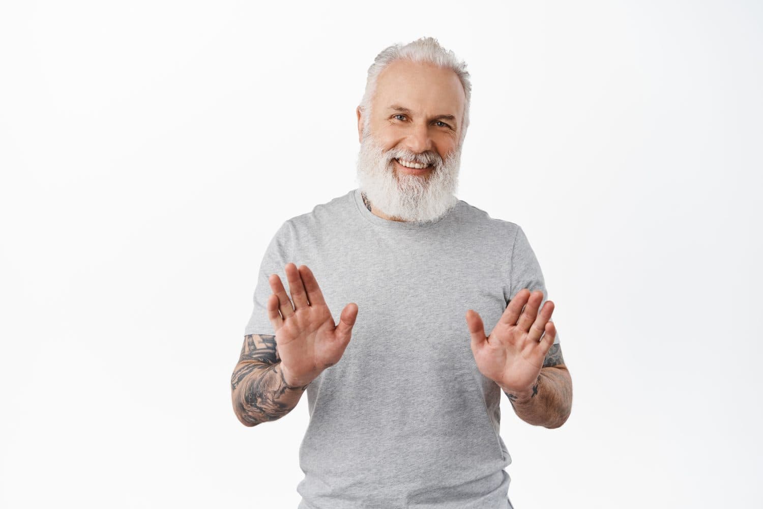 No thank you. Smiling happy old guy with tattoos shaking hands to refuse, rejecting offer, politely decline something, standing in grey t-shirt against white background