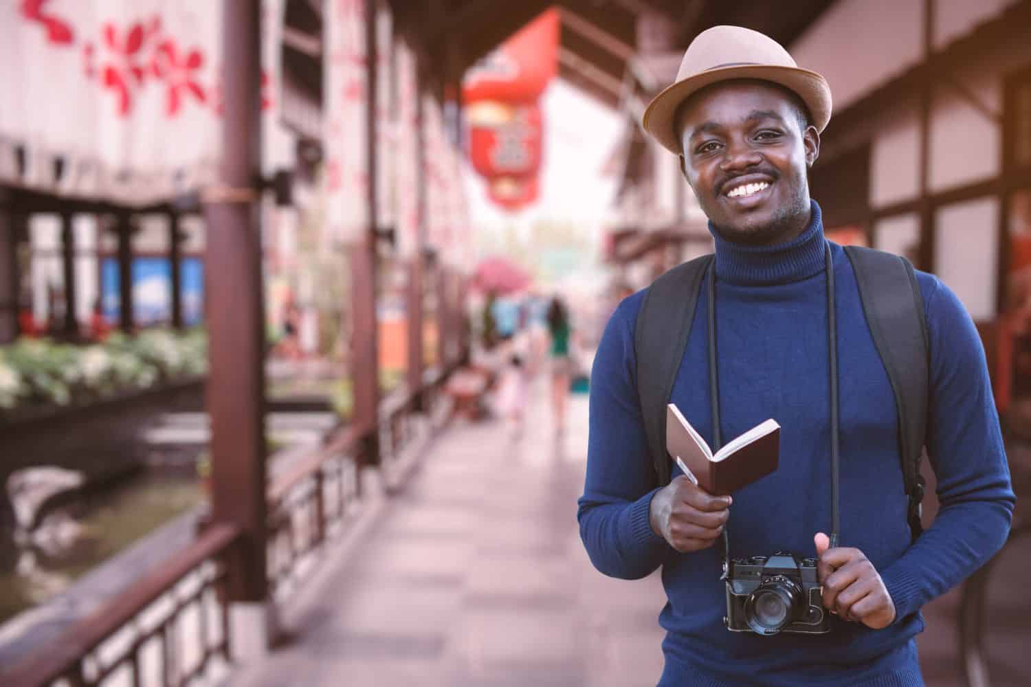 African traveler man travel in asia with holding passport and vintage camera