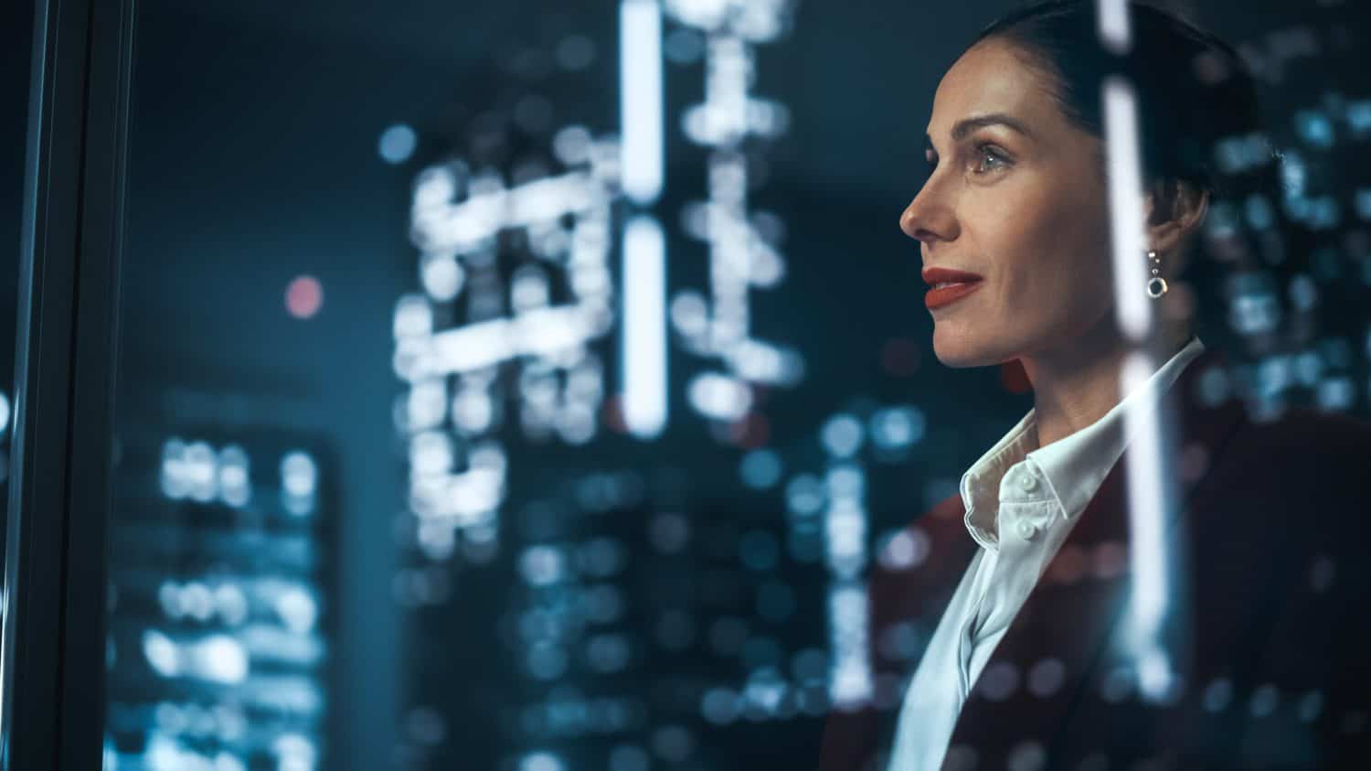 Successful Businesswoman in Stylish Suit Working on Top Floor Office Overlooking Night City. High Achievement Female CEO of Humanitarian Investment Fund, Human Face of Sustainable Corporate Governance