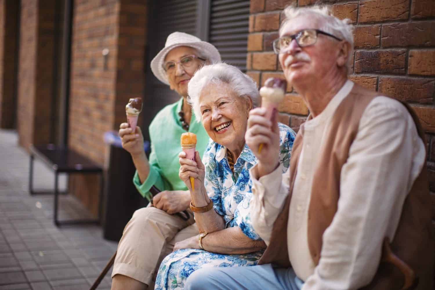 Portrait of three senior friends in the city, eating ice cream on a hot summer day.