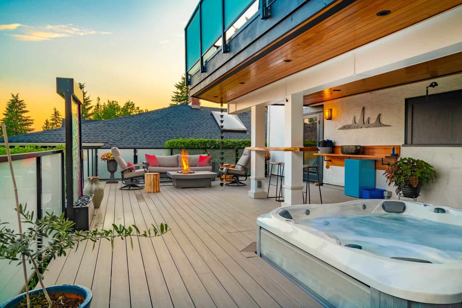 expansive deck with hot tub fire table bar and bar stools outdoor living twilight skies sunset summer night inviting outside space