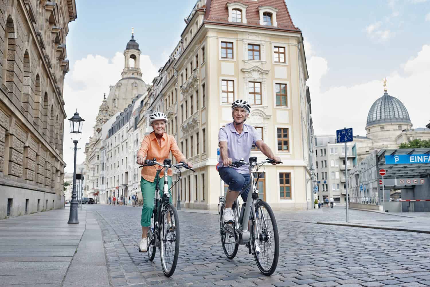 Senior tourists riding electric bicycle against frauenkirche cathedral at dresden- germany