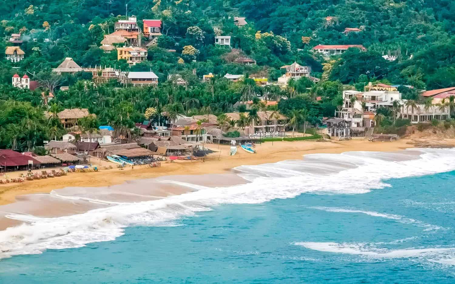 Punta Cometa and Playa Mazunte sunset beach panorama view with waves cliff cliffs mountain mountains hill hills rocks rock in tropical nature jungle forest in Mazunte Oaxaca Mexico.