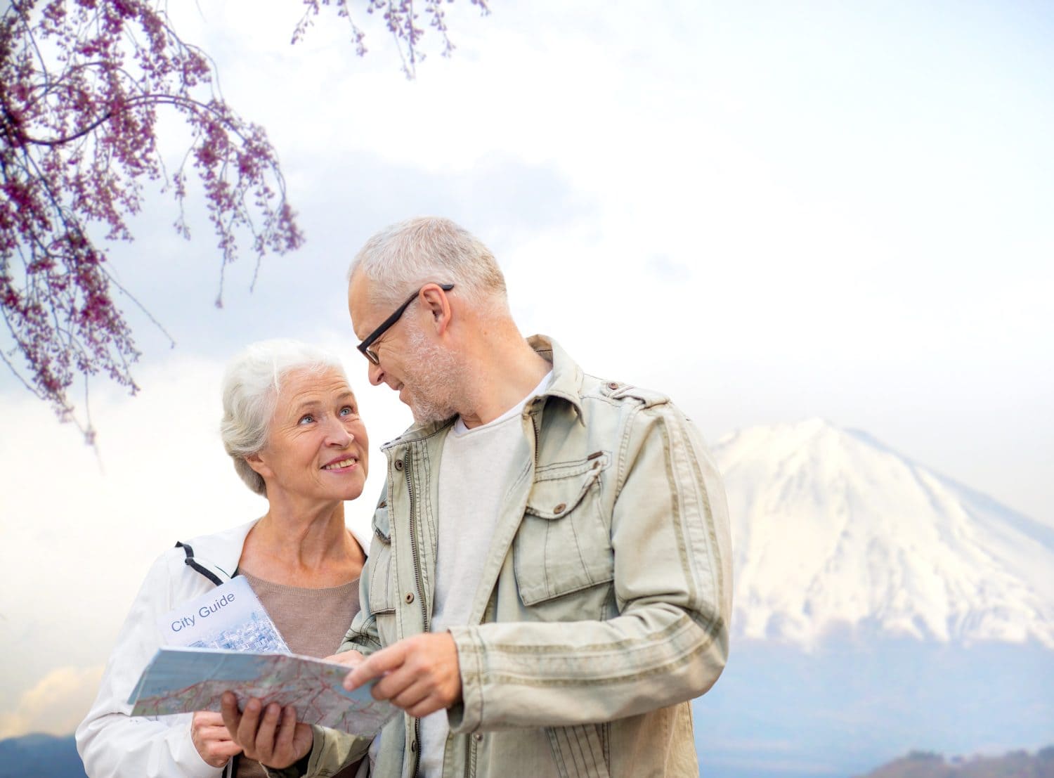 family, age, tourism, travel and people concept - senior couple with map and city guide talking over japan mountains background