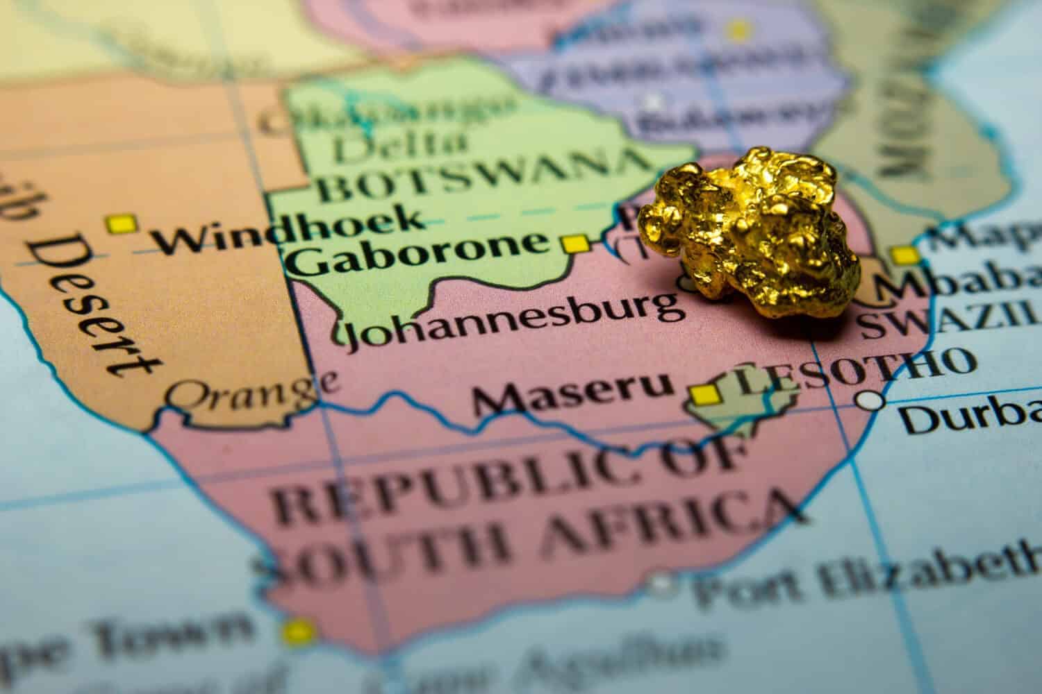 Close-up of a gold nugget on top of a map of South Africa