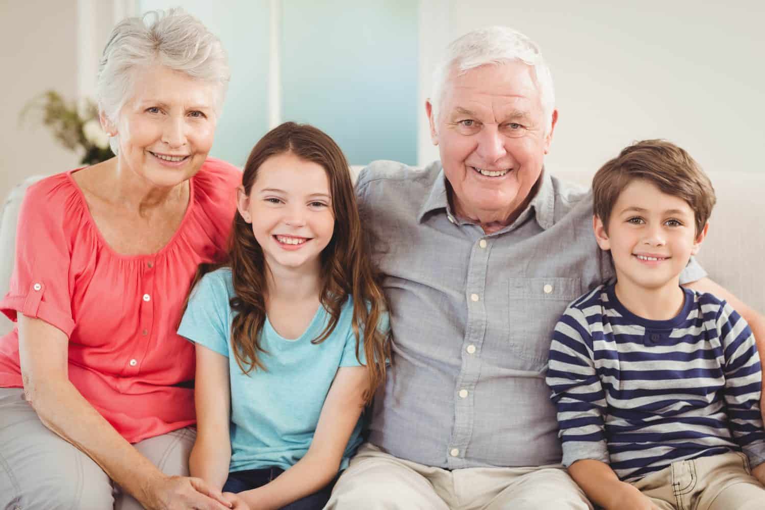 Portrait of grandparents and grandchildren sitting together on sofa in living room