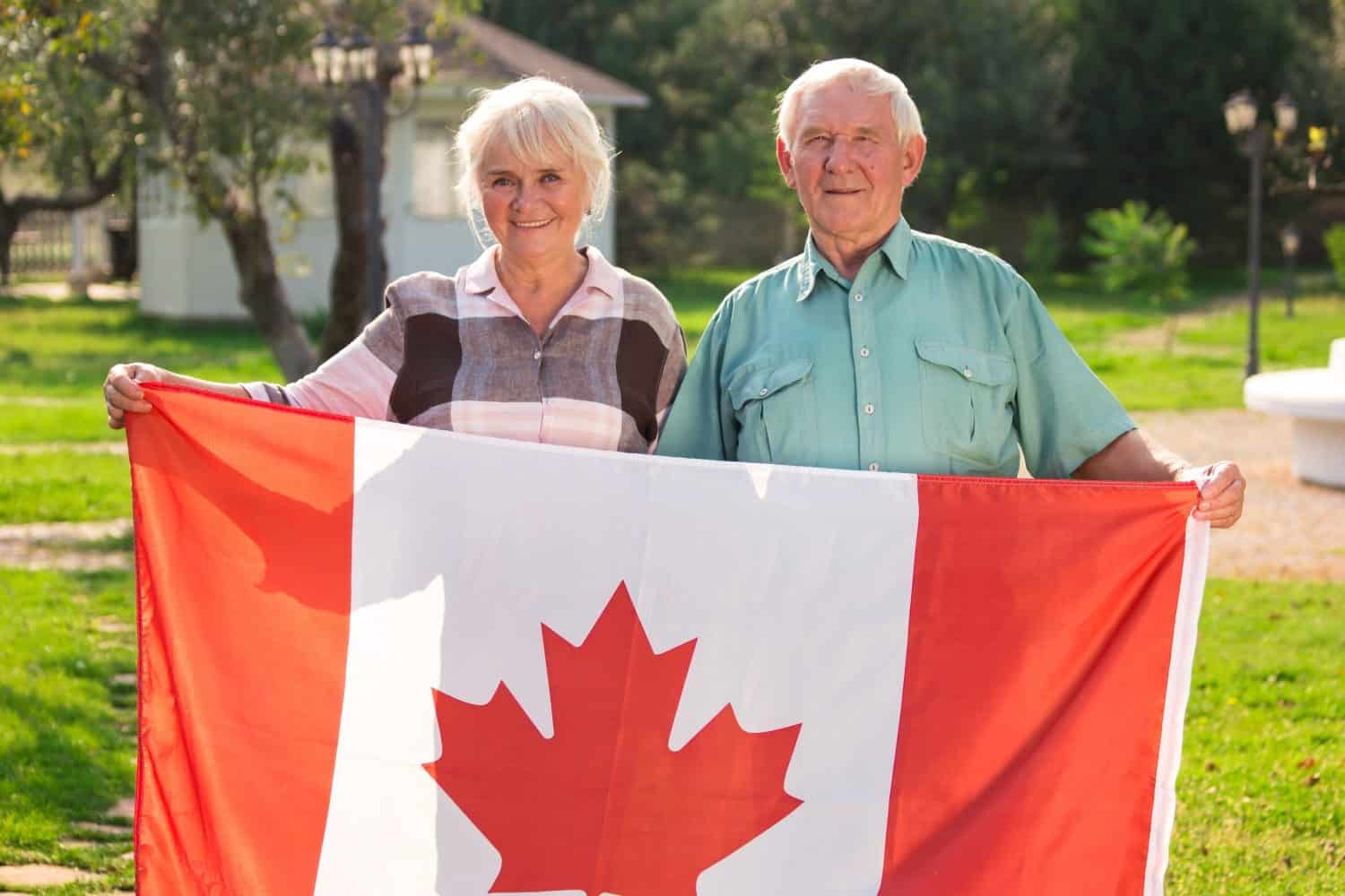 Senior couple holding Canadian flag. Man and woman outdoors. Life in Canada.