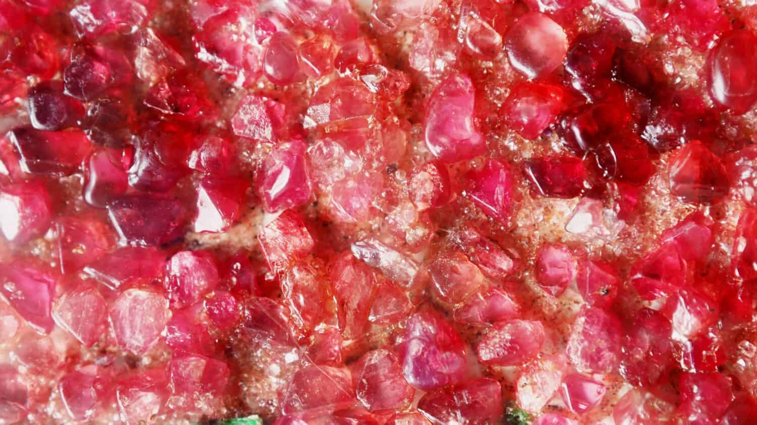 Closeup shot of beautiful natural tumbled unpolished ruby gemstones for background / backdrop / wallpaper.